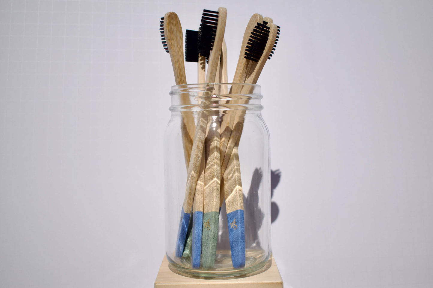 Biodegradable bamboo toothbrushes in a glass jar, featuring eco-friendly designs by Wild & Stone.
